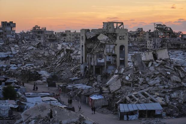 Palestinians walk amid war-damaged buildings in Gaza City.