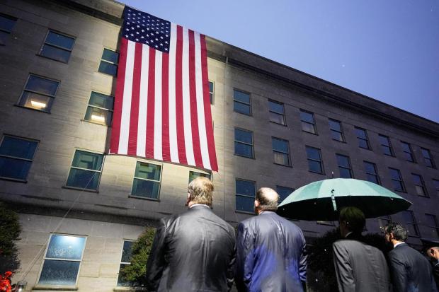 Secretary of Defense Pete Hegseth, Chairman of the Joint Chiefs, Air Force Gen. Dan Caine, and other officials, watch as the flag is unfurled at the Pentagon, Friday, Sept. 11, 2026 in Arlington, Va. (AP Photo/Manuel Balce Ceneta)