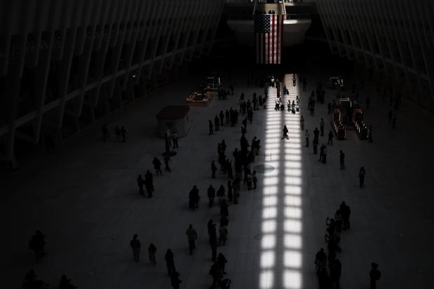 People make a path as two columns of light, representing the World Trade Center, appear on the floor appear on the floor inside the Oculus on the 25th anniversary of the Sept. 11, 2001, terrorist attacks, Friday, Sept. 11, 2026, in New York. (AP Photo/Heather Khalifa)