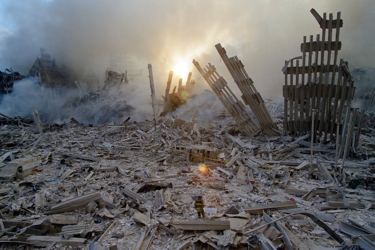 A New York City firefighter steps through the wreckage of the collapsed World Trade Center on the morning of Sept. 12, 2001.