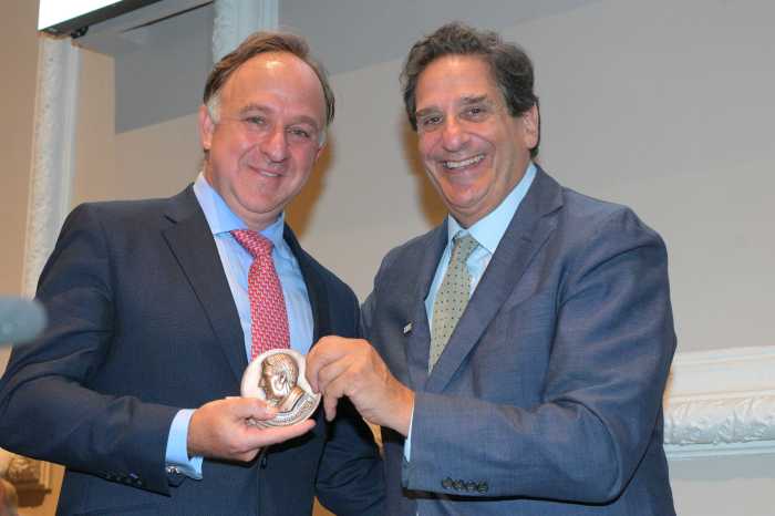 two men holding an award and wearing suits