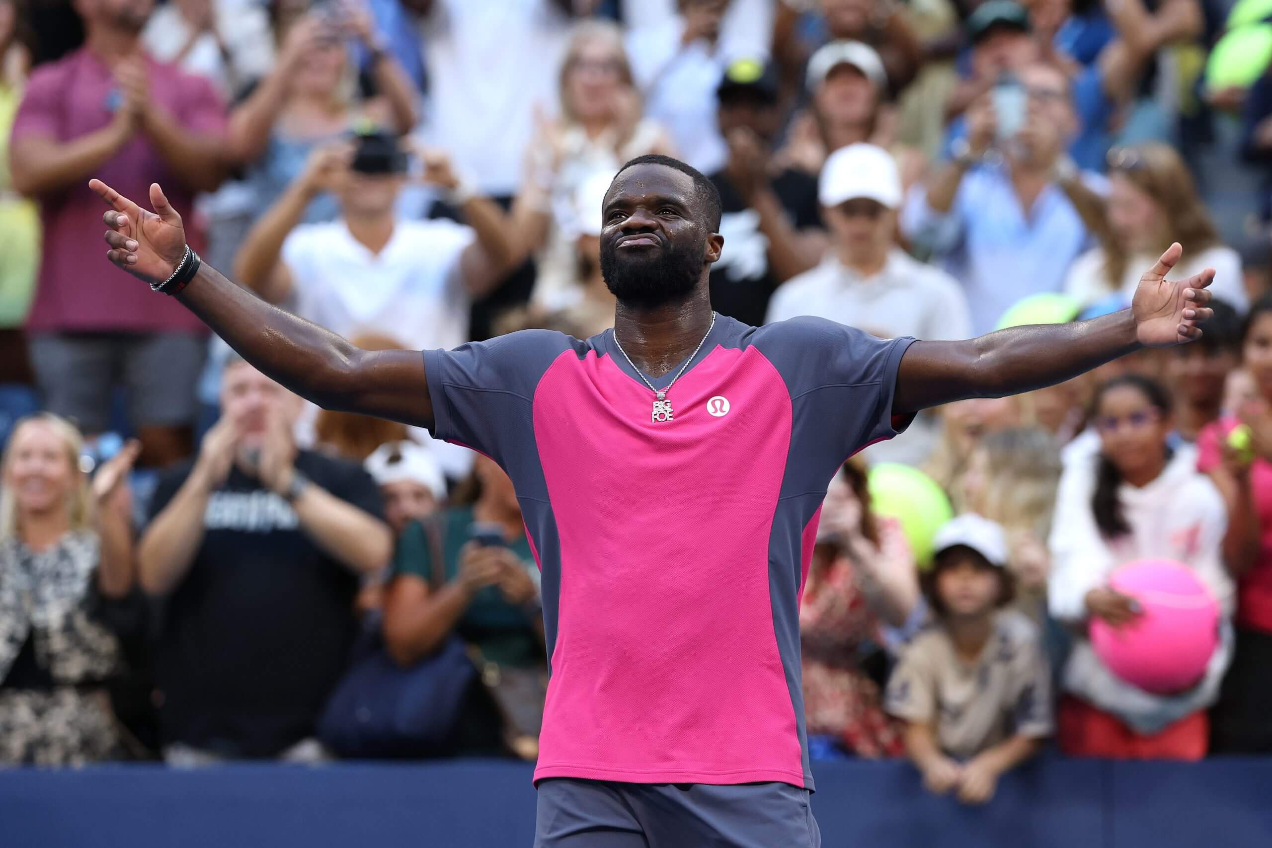 Frances Tiafoe raises his arms and takes in the applause of tennis fans behind him.