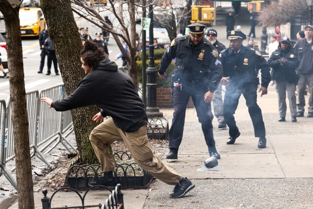 TOPSHOT - A left-wing activist flees after throwing a homemade explosive device towards police during a protest organized by far-right influencer Jake Lang against alleged "Islamification" and to ask for a "stop of public Muslim prayer" in New York, in front of Gracie Mansion, New York mayor Zohran Mamdani's official residence, in New York on March 7, 2026. (Photo by CHARLY TRIBALLEAU / AFP via Getty Images)
