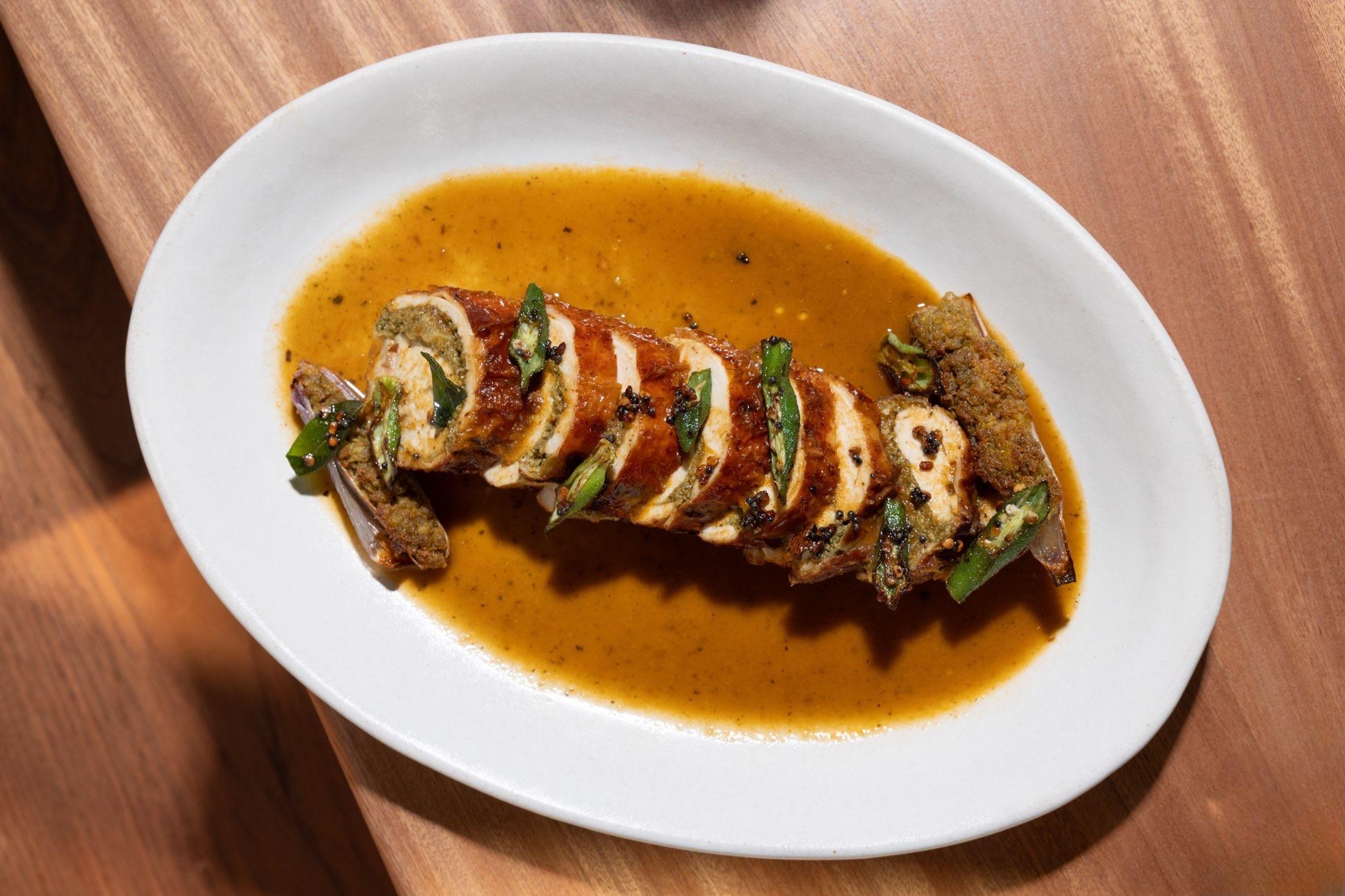 A sliced-up chicken roll on a plate with broth.