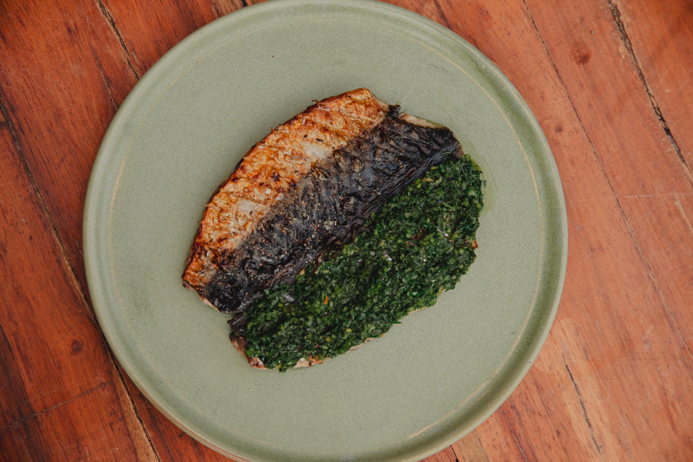 A plate of grilled fish and a green chunky sauce.