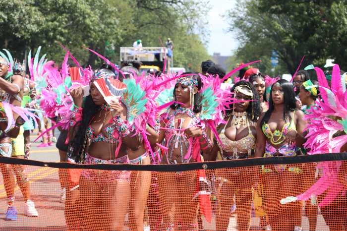 Masqueraders from SkyMaxx Mas behind police mesh during the West Indian American Day Carnival Day Parade in 2025.