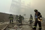 FILE - In this Sept. 11, 2001 file photo, firefighters work beneath the destroyed mullions, the vertical struts that once faced the outer walls of the World Trade Center towers, after a terrorist attack on the twin towers in New York.