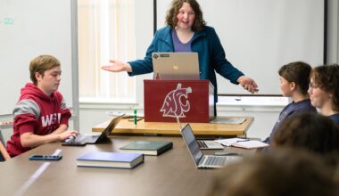 Lucy Stutesman stands at a podium during a meeting of Daily Evergreen staff