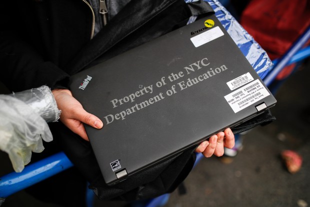 A student receives her school laptop for home study at the Lower East Side Preparatory School Thursday, March 19, 2020, in New York. (John Minchillo / AP)