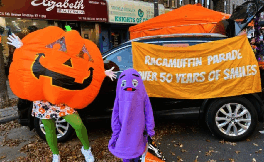 A giant jack-o-lantern costume and a purple monster pose beside a Ragamuffin Parade banner on Third Avenue in Bay Ridge