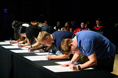 Queens students signing honor code at Sed Min