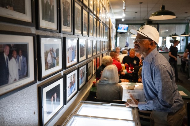 Patron Cosmas Agwu looks over wall covered in photos of Bill Ficke with athletes during the annual 