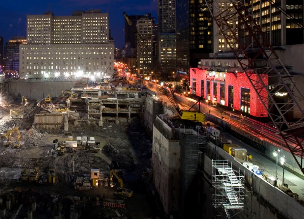 Construction continues at the World Trade Center site Friday, Dec. 5, 2008 in New York. The Century 21 department store, right, is covered in red light for the holiday season. (Mark Lennihan/AP)