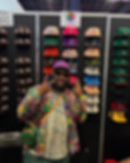 A man in a baseball cap standing in front of other baseball caps.