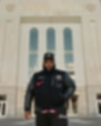 A man in a baseball cap standing in front of a building