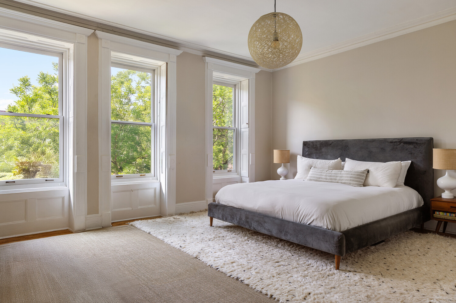 bedroom with pale walls, three windows
