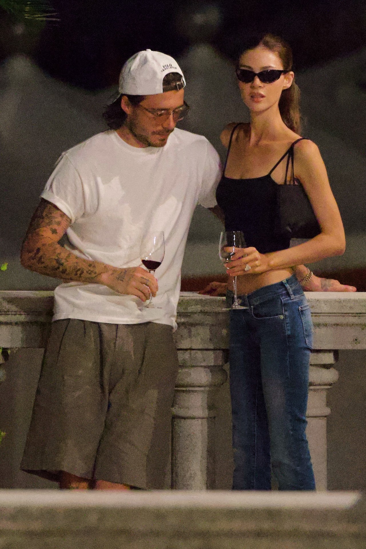Brooklyn Beckham and Nicola Peltz kissing while holding glasses of wine in Venice