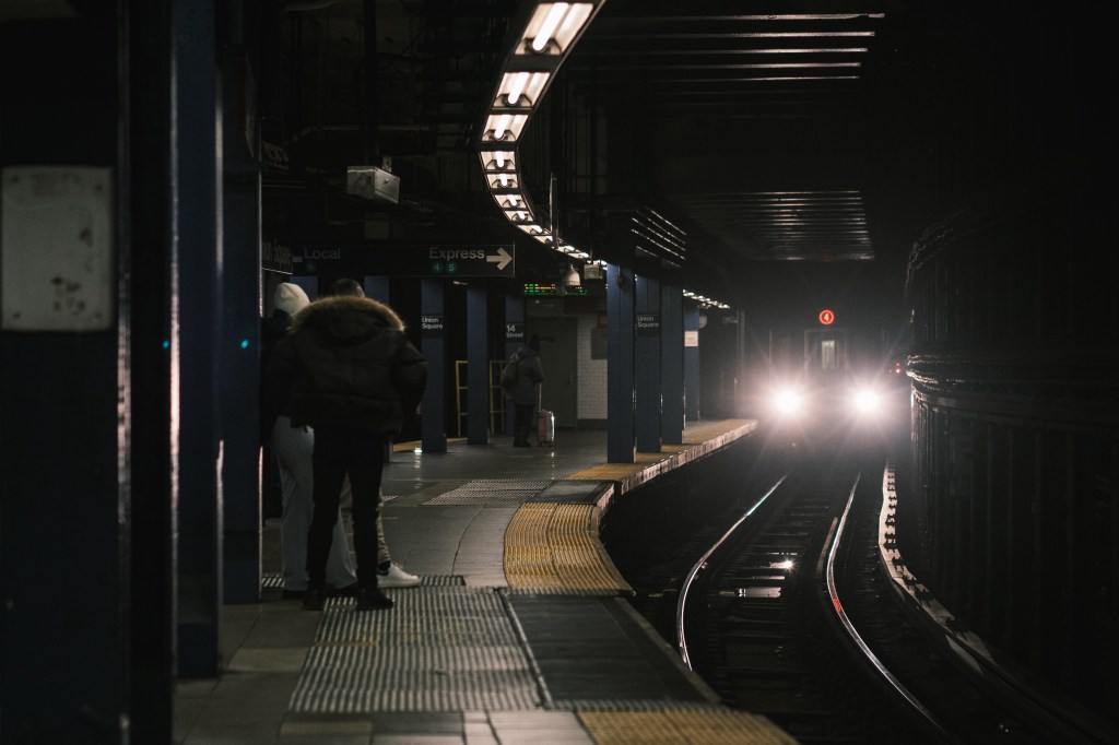 Commuters wait at the Union Square subway station as a 6 train approaches.