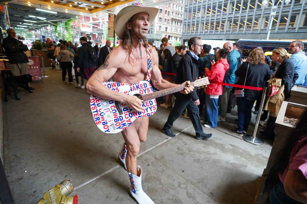 The Naked Cowboy playing a guitar in front of a crowd.
