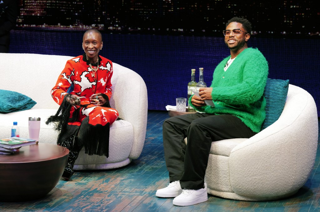 Cynthia Erivo and Kwame Onwuachi sit on chairs on a stage.