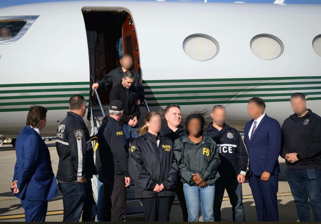 Davud Ansariy, an extradited prisoner, being escorted off a private jet by law enforcement officials.