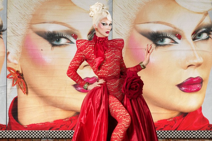Naya Thorn wearing a red lace dress with one hand on her hip.