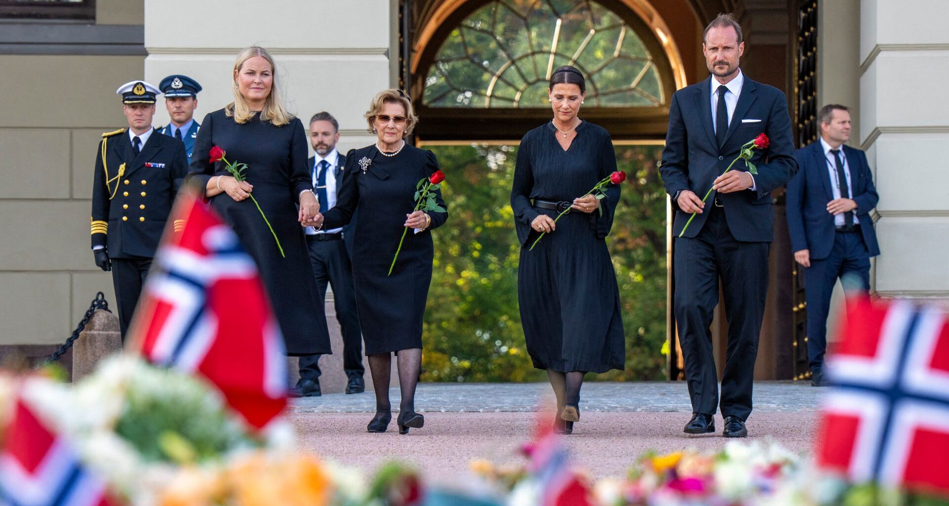 Queen Mette-Marit , Queen Sonja, Princess Martha Louise and King Haakon wearing black outfits holding roses