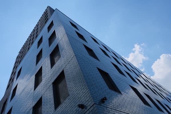 The exterior of the affordable housing building, from the ground, pointed toward the sky, shows a dark brick facade.
