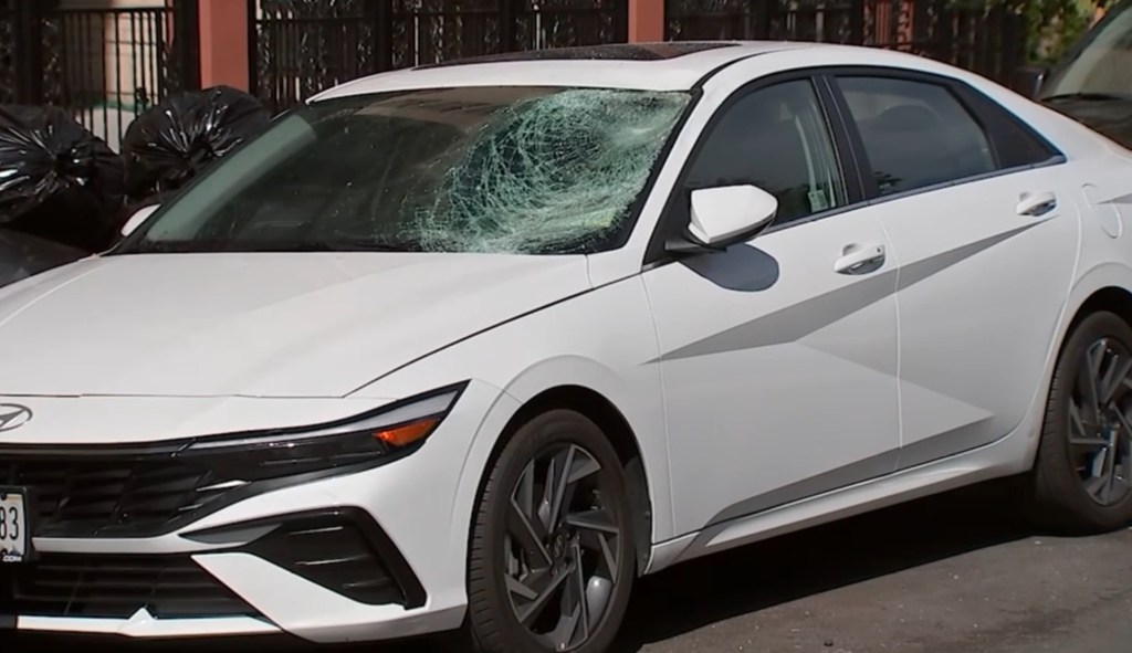 A white Hyundai sedan with a shattered windshield, believed to be involved in a hit-and-run crash.