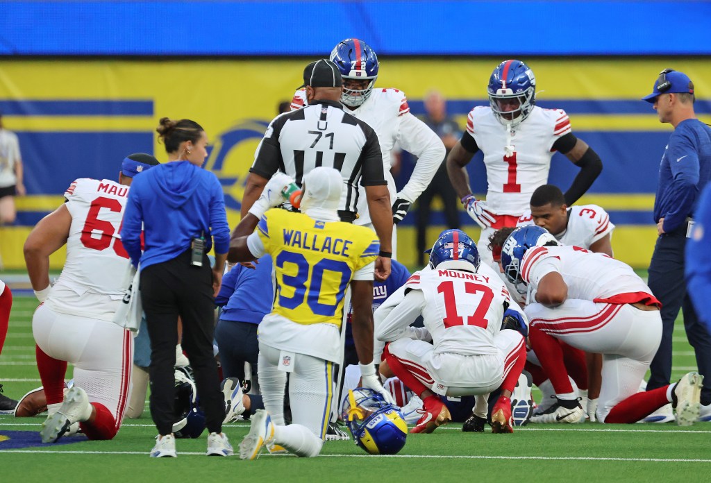 New York Giants quarterback Jaxson Dart (6) is checked by his teammates and staff after taking a hard hit in a football game.