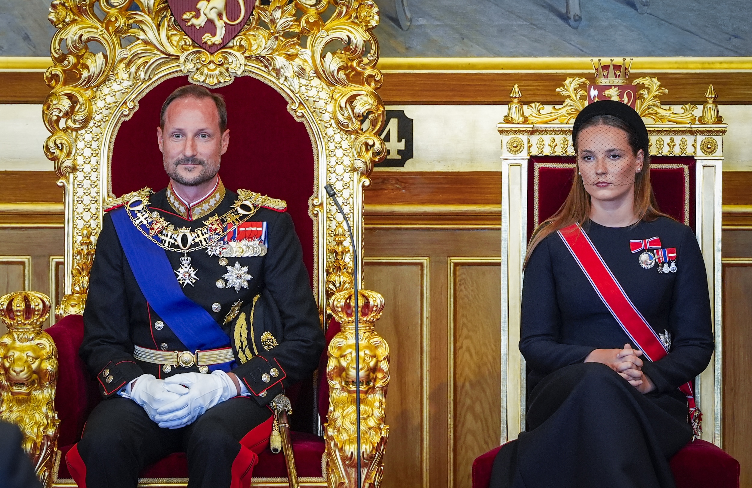 King Haakon sitting on a throne next to Crown Princess Ingrid Alexandra