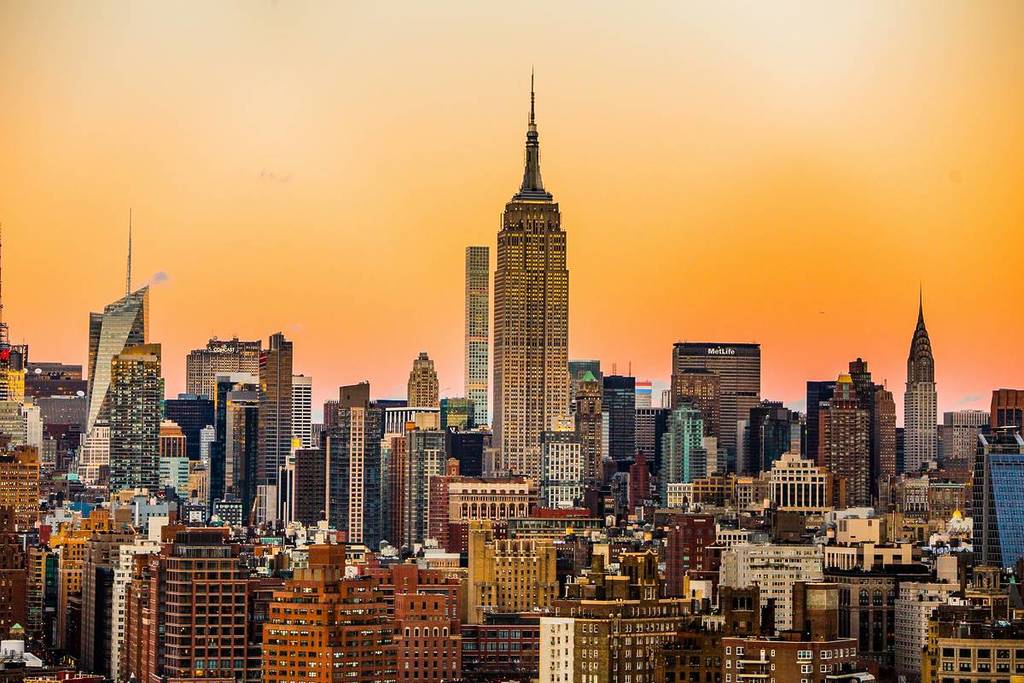 The New York skyline before an orange sky.
