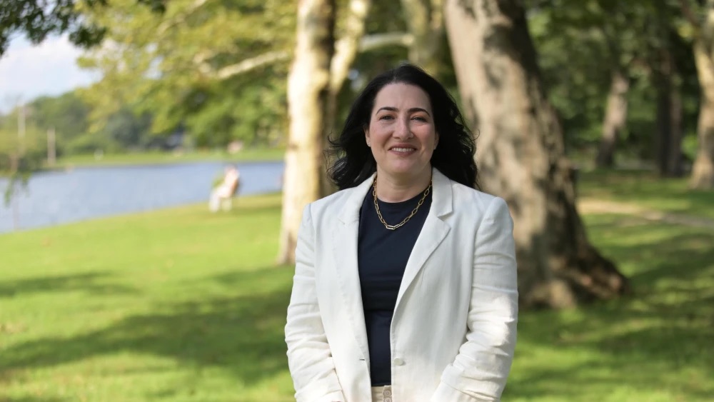 Lisa Vider smiling outdoors in a park near a body of water.