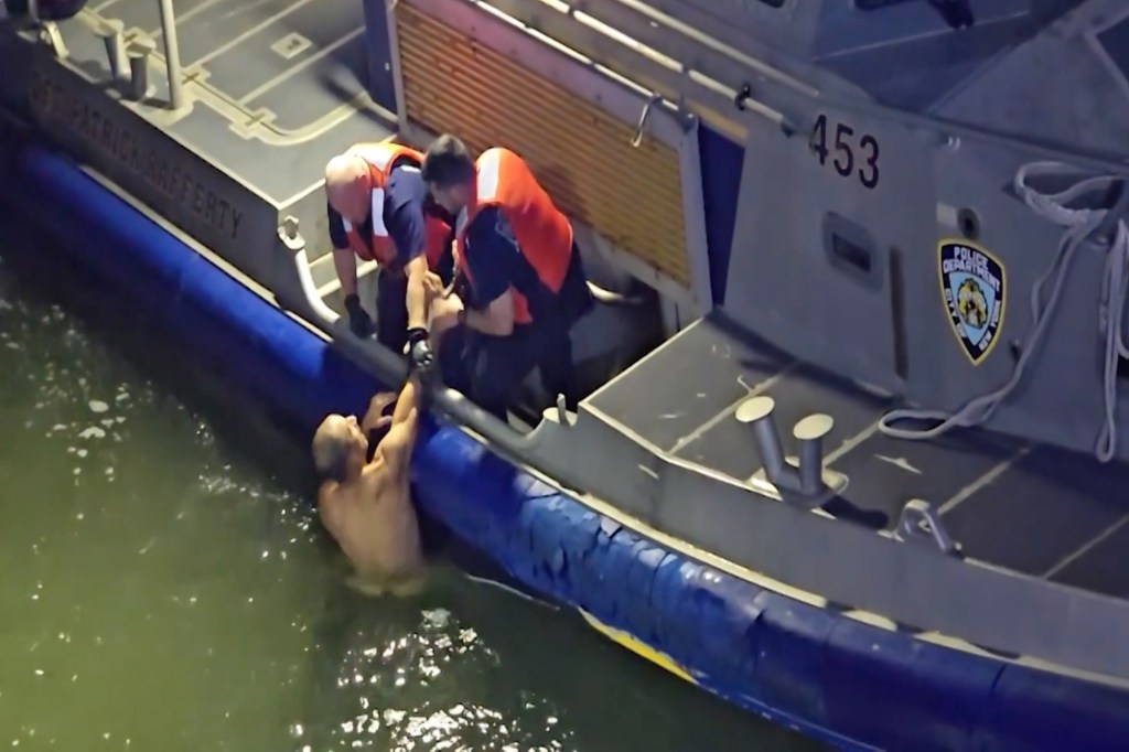 New York City Police officers in a boat pull a naked man out of the East River.
