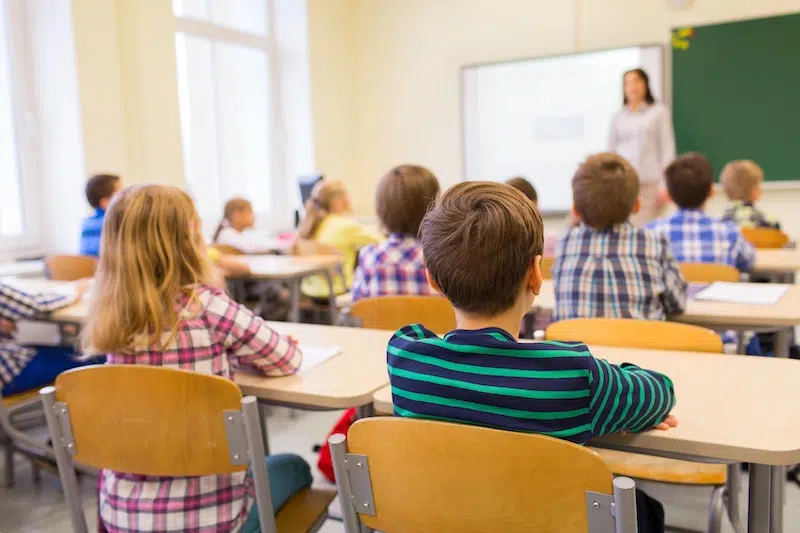 Kids at desks in a classroom.