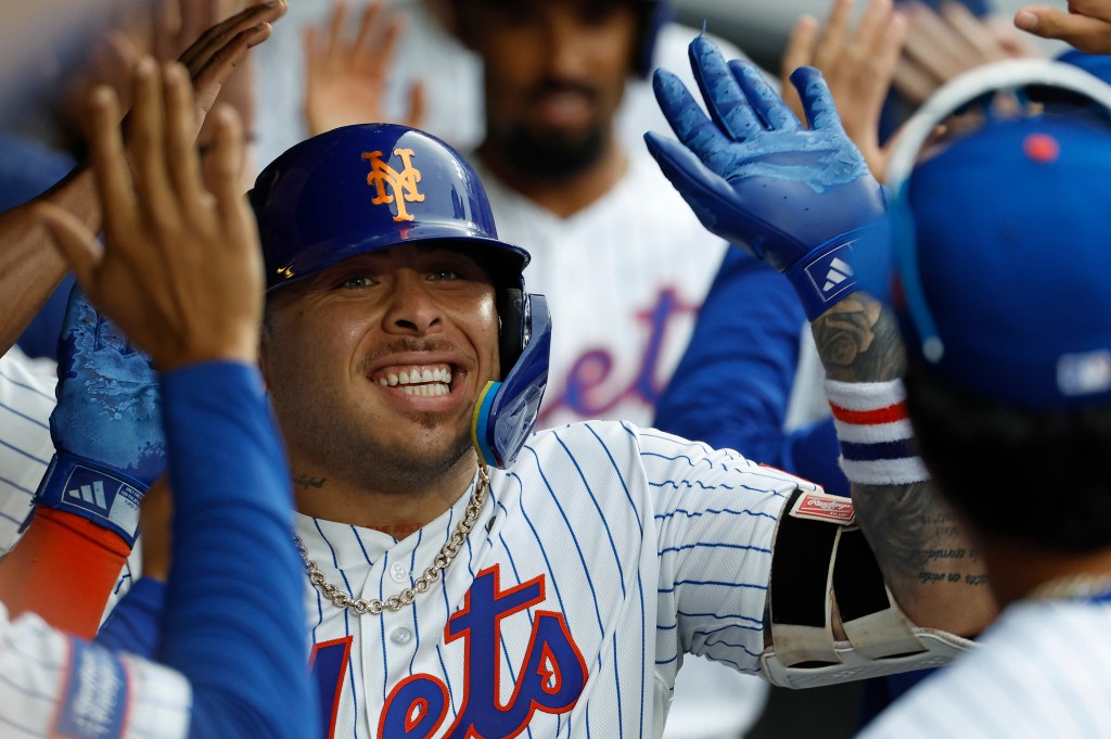 New York Mets catcher Francisco Alvarez is greeted by his teammates in the dugout after scoring on his three-run home run.