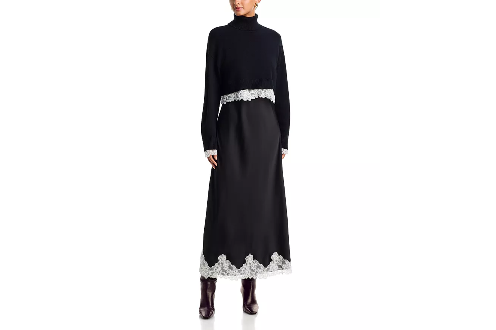 A model wearing a black turtleneck sweater over a black slip dress with white lace trim at the hem and cuffs, paired with dark brown boots.