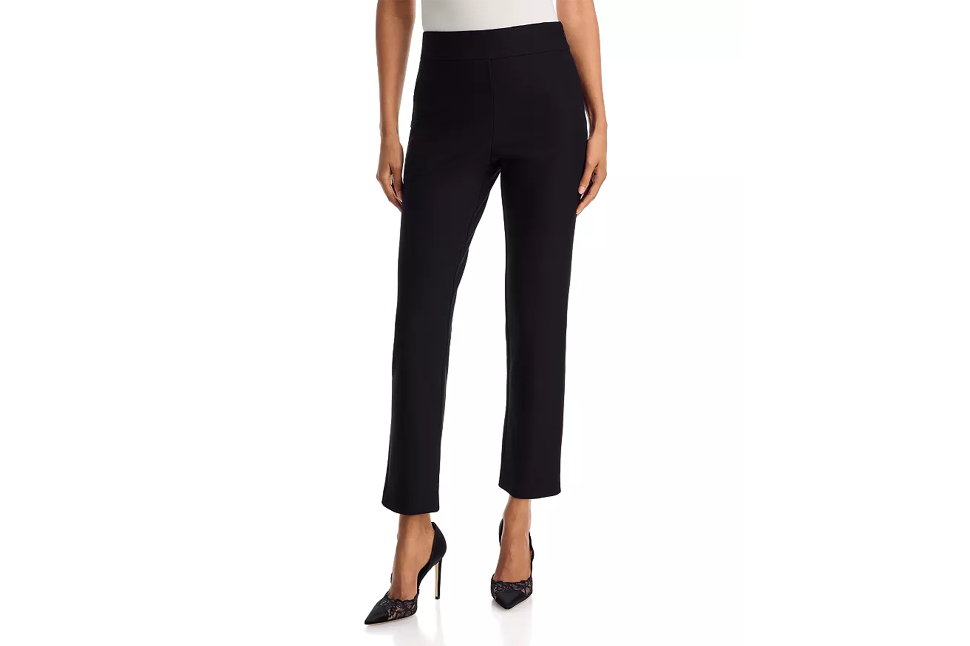 A person models black ankle-length pants with a wide elastic waistband and black pointed-toe heels with lace accents.