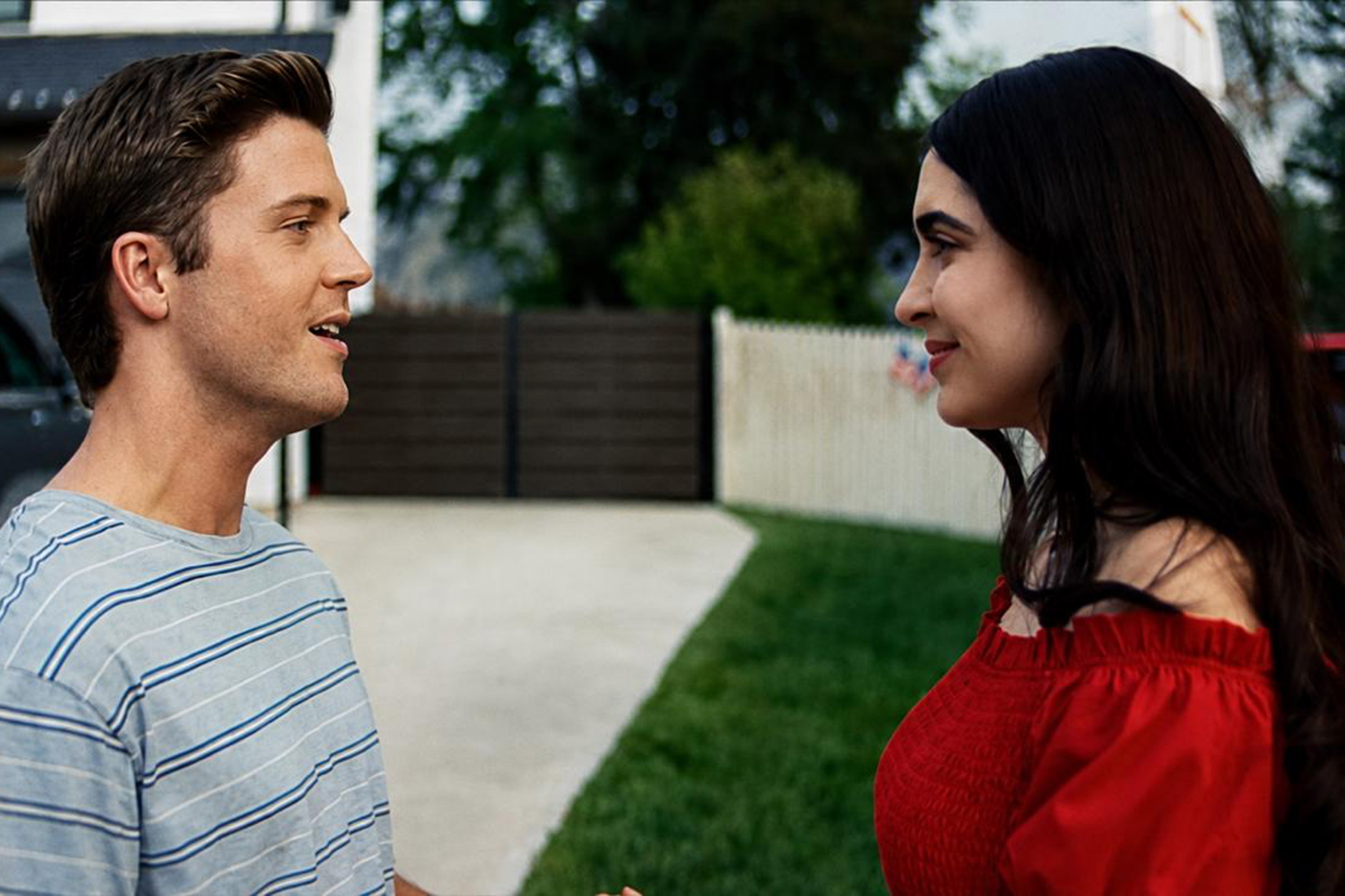 Paulina Reyes, right, and a co-star smile at each other in a scene from the film, standing in a suburban driveway.