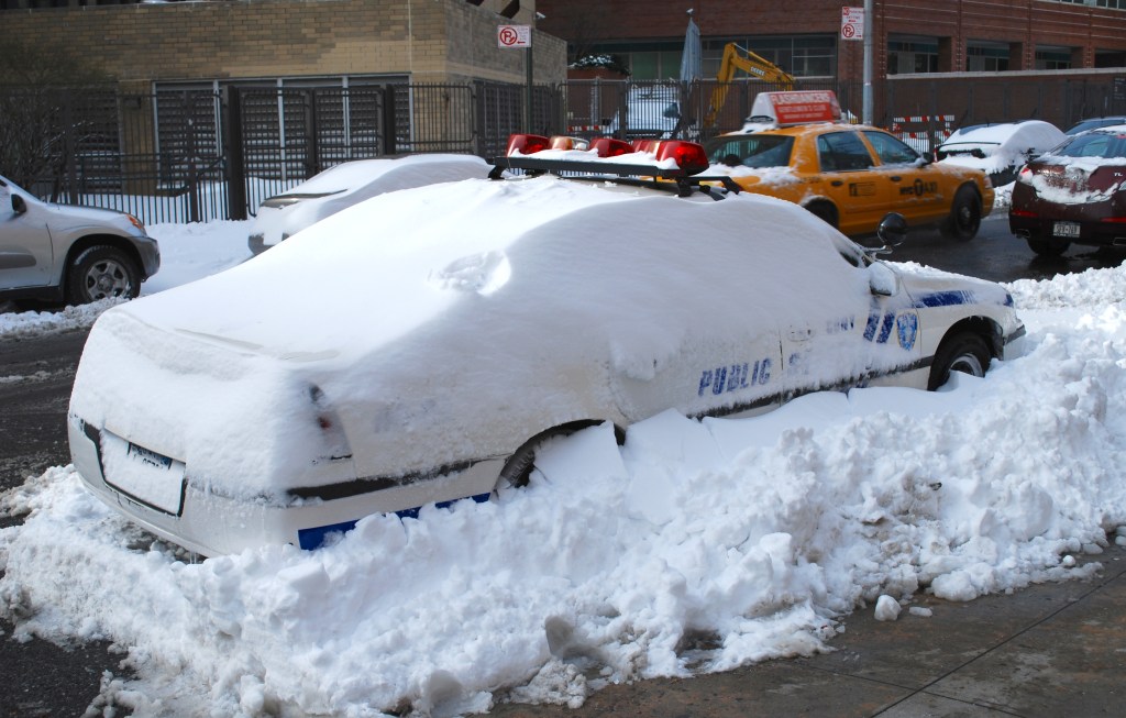 An NYPD squad car buried in snow.