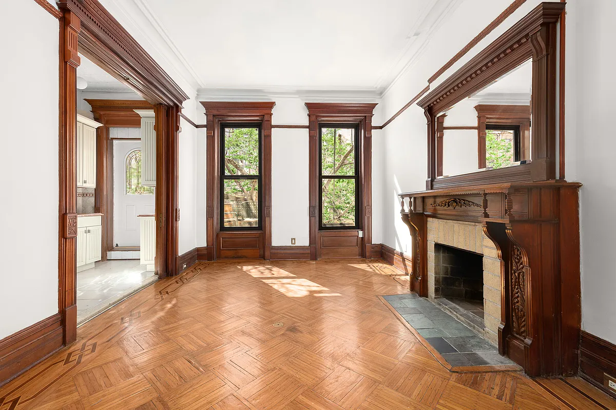 room with a mantel and a view into a kitchen
