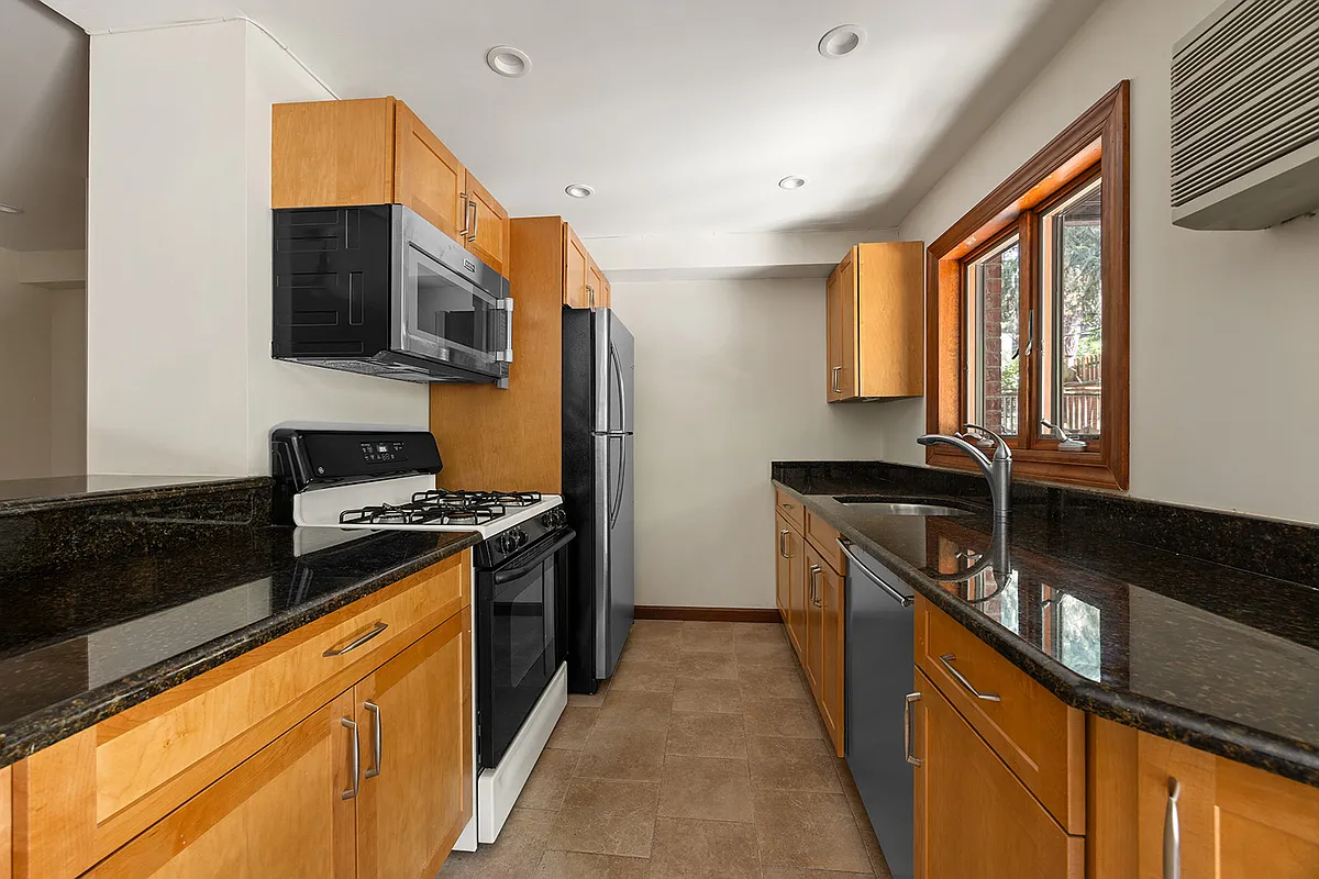 galley kitchen with wood cabinets, black counters