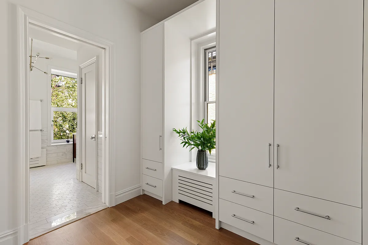 dressing room with white built-in storage and a view into a bathroom with white tile floor