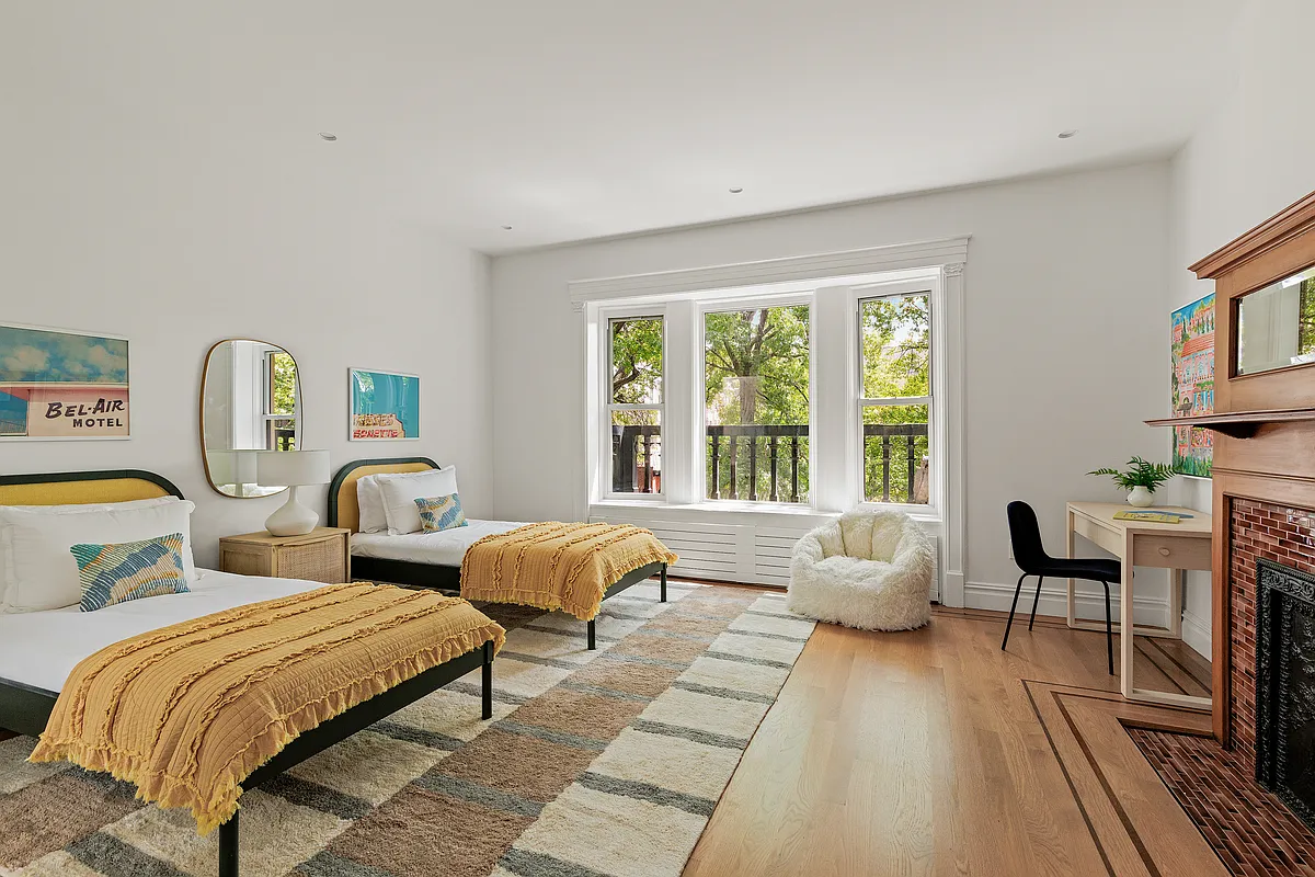 bedroom with wood floor, white walls, wood mantel