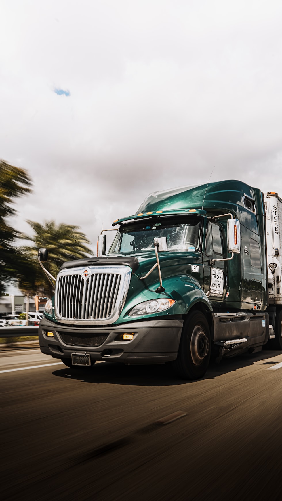 a green semi truck driving down a street