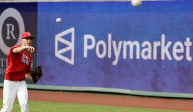 A Major League baseball player throws a ball during warmups, while a large sign advertising Polymarket is seen on the outfield wall.
