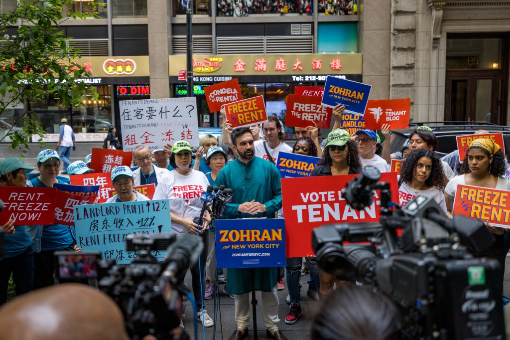 Zohran Mamdani speaks at a "Rent Freeze" press conference as protesters hold signs for rent freezes and for Zohran.