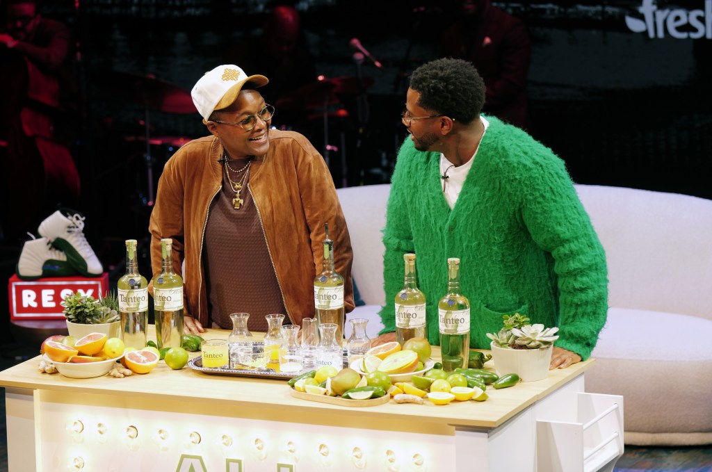 Sam Jay and Kwame Onwuachi talking behind a counter with ingredients for cocktails.