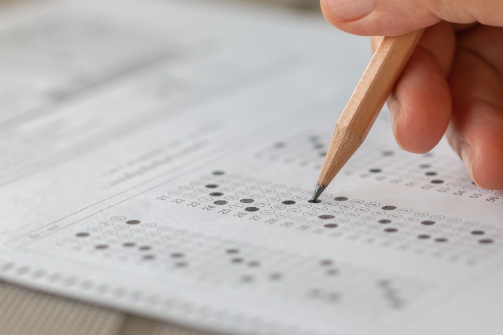 A student fills in circles on a multiple-choice answer sheet with a pencil.