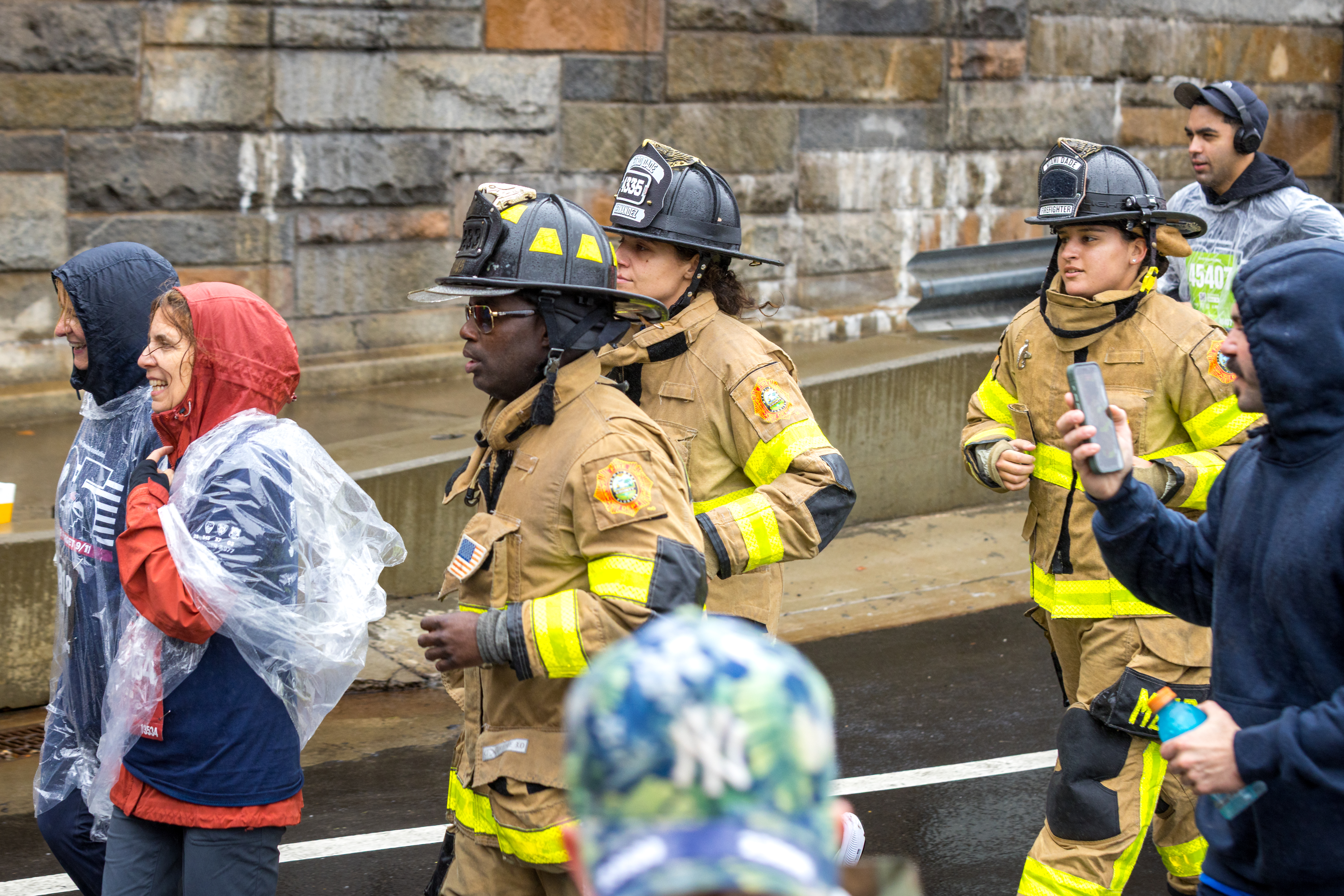 Participants in firefighter gear and rain ponchos walk during the Tunnel to Towers 5K Run & Walk.